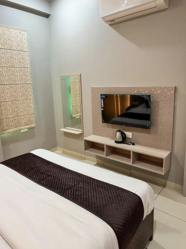 Bedroom with wall-mounted TV, kettle and storage unit